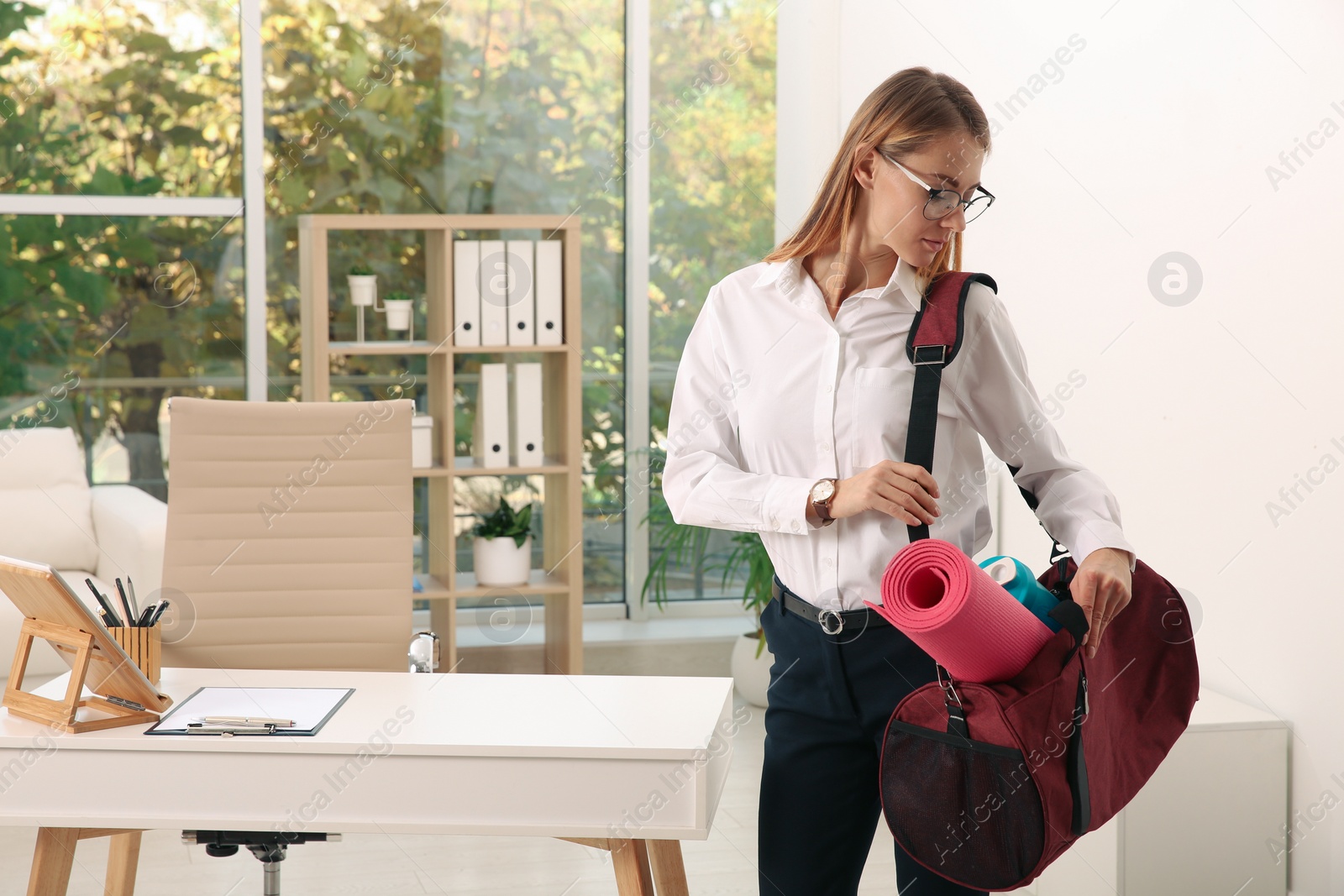 Photo of Beautiful businesswoman with sports bag in office