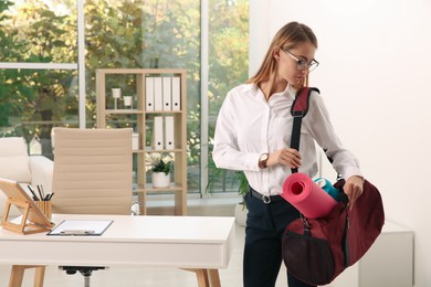 Beautiful businesswoman with sports bag in office