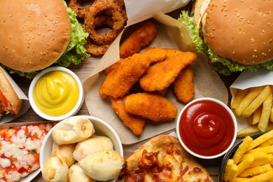 French fries, burgers and other fast food as background, top view