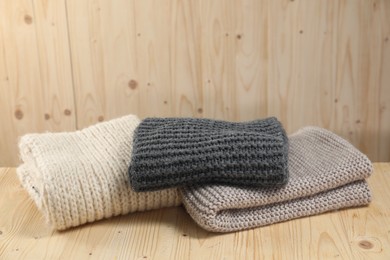 Photo of Stylish soft knitted scarfs on wooden table