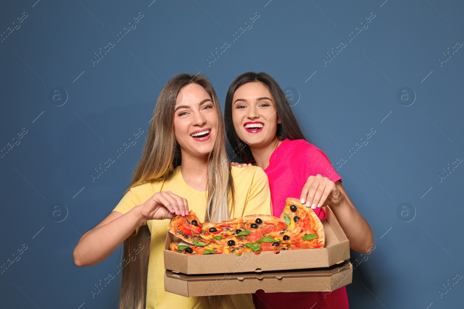 Photo of Attractive young women with delicious pizza on color background