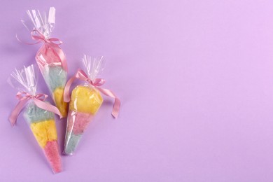 Photo of Packaged sweet cotton candies on violet background, flat lay. Space for text