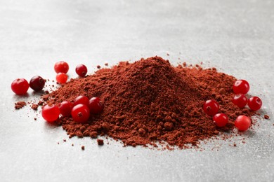 Photo of Pile of cranberry powder and fresh berries on light table, closeup