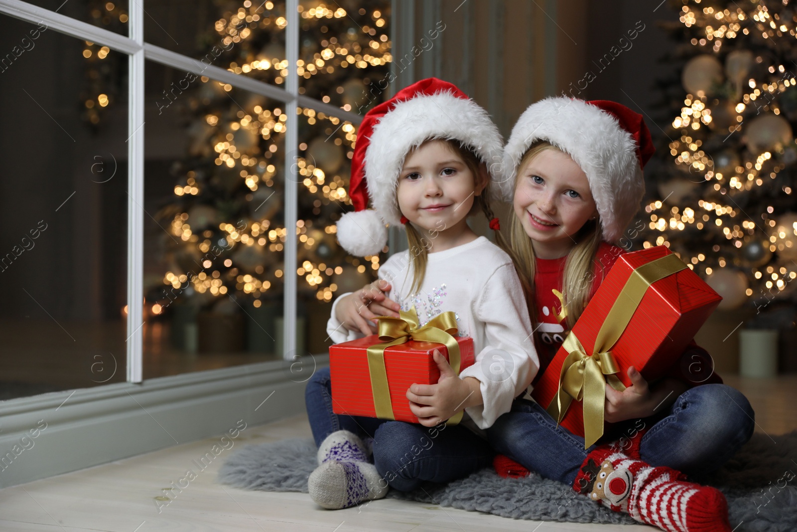 Photo of Cute little children with Christmas gifts at home