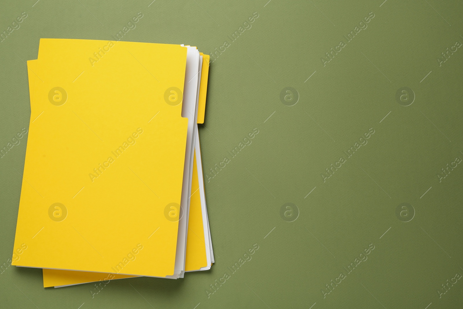 Photo of Yellow files with documents on olive background, top view. Space for text