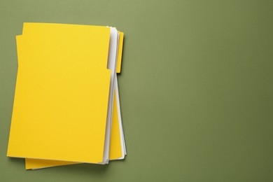 Photo of Yellow files with documents on olive background, top view. Space for text