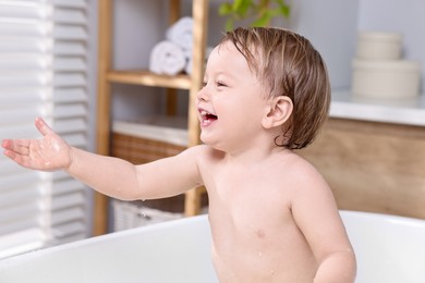 Photo of Cute little child bathing in tub at home