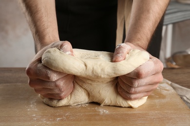 Male baker preparing bread dough at table, closeup