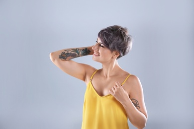 Young woman with tattoo on color background