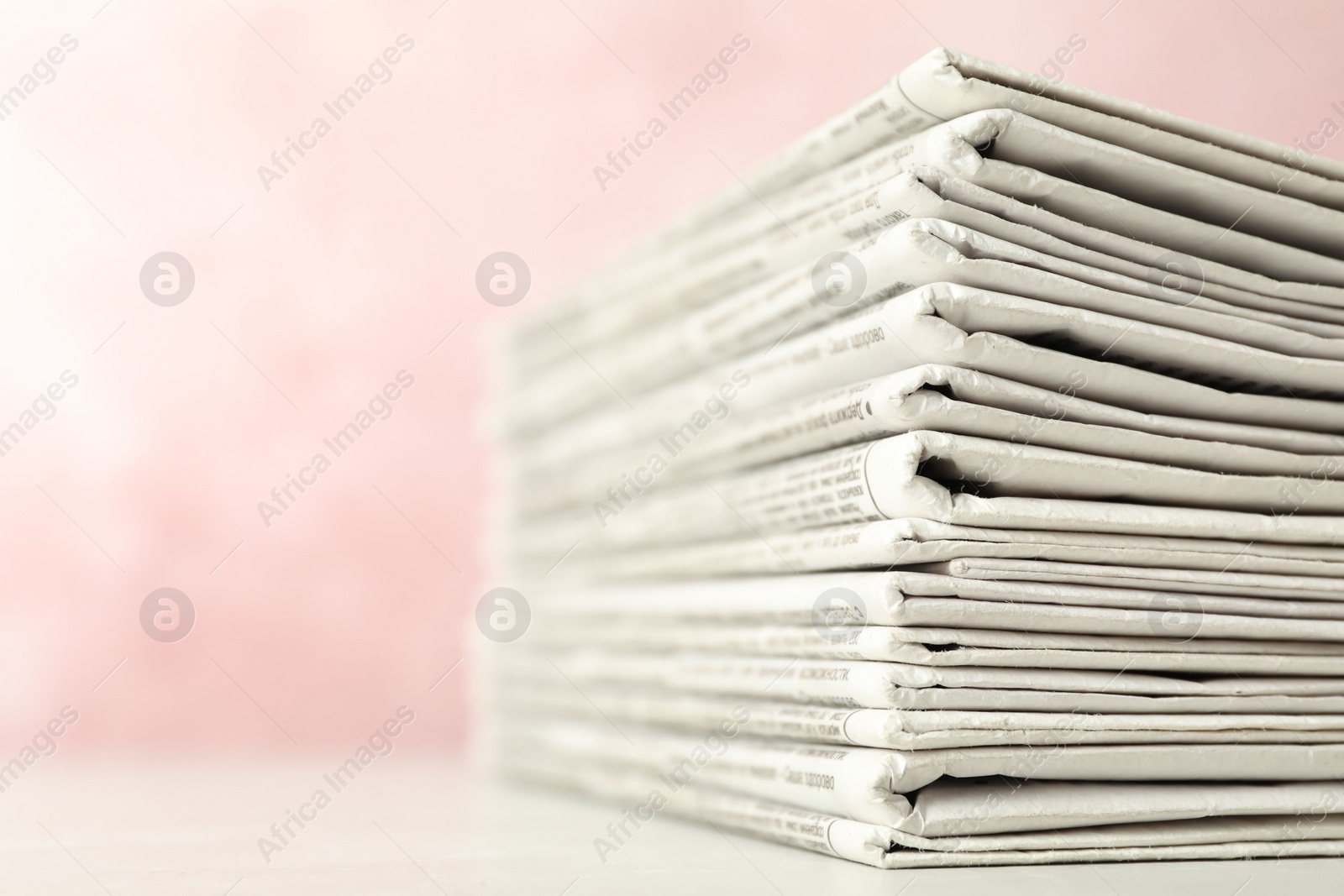 Photo of Stack of newspapers on pink background, closeup. Journalist's work