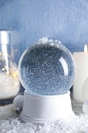 Magical empty snow globe with Christmas decorations and candles on table