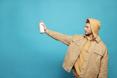 Photo of Handsome man holding white can of spray paint on light blue background. Space for text
