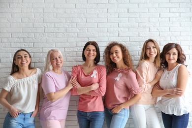 Group of women with silk ribbons near brick wall. Breast cancer awareness concept