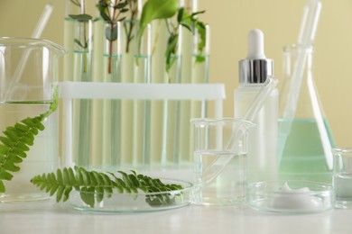 Natural ingredients for cosmetic products and laboratory glassware on white table