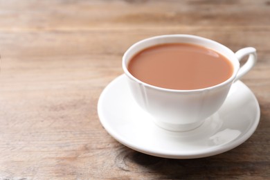 Photo of Delicious tea with milk in white cup on wooden table