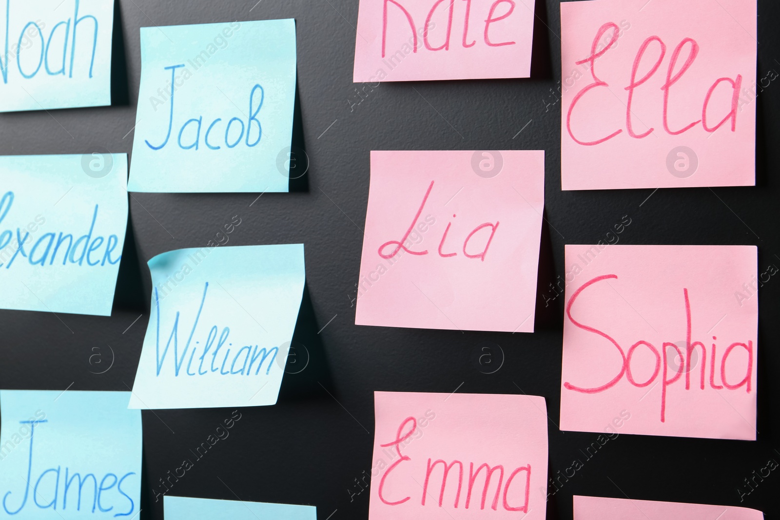 Photo of Sticky notes with baby names on black board, closeup