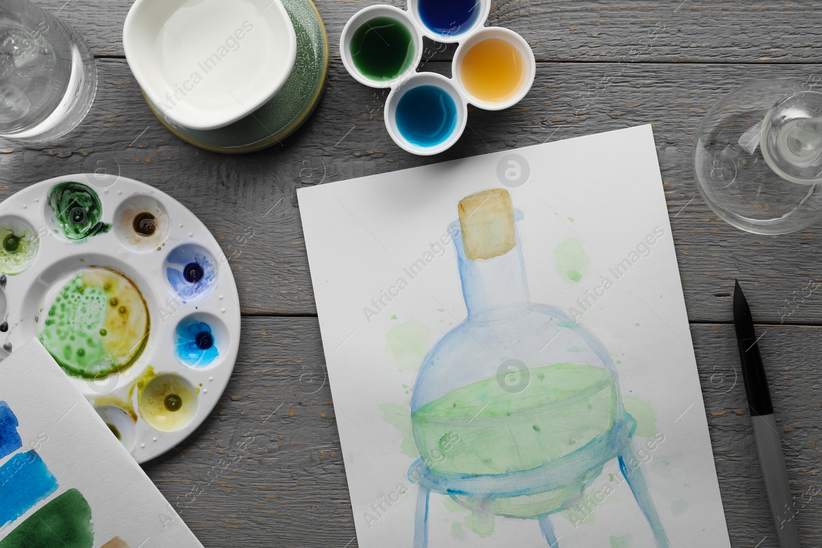 Photo of Flat lay composition with watercolor painting of flask and brush on grey wooden table