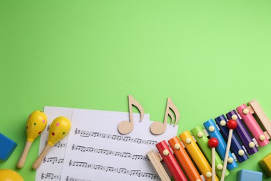 Photo of Tools for creating baby songs. Flat lay composition with maracas and xylophone on green background. Space for text