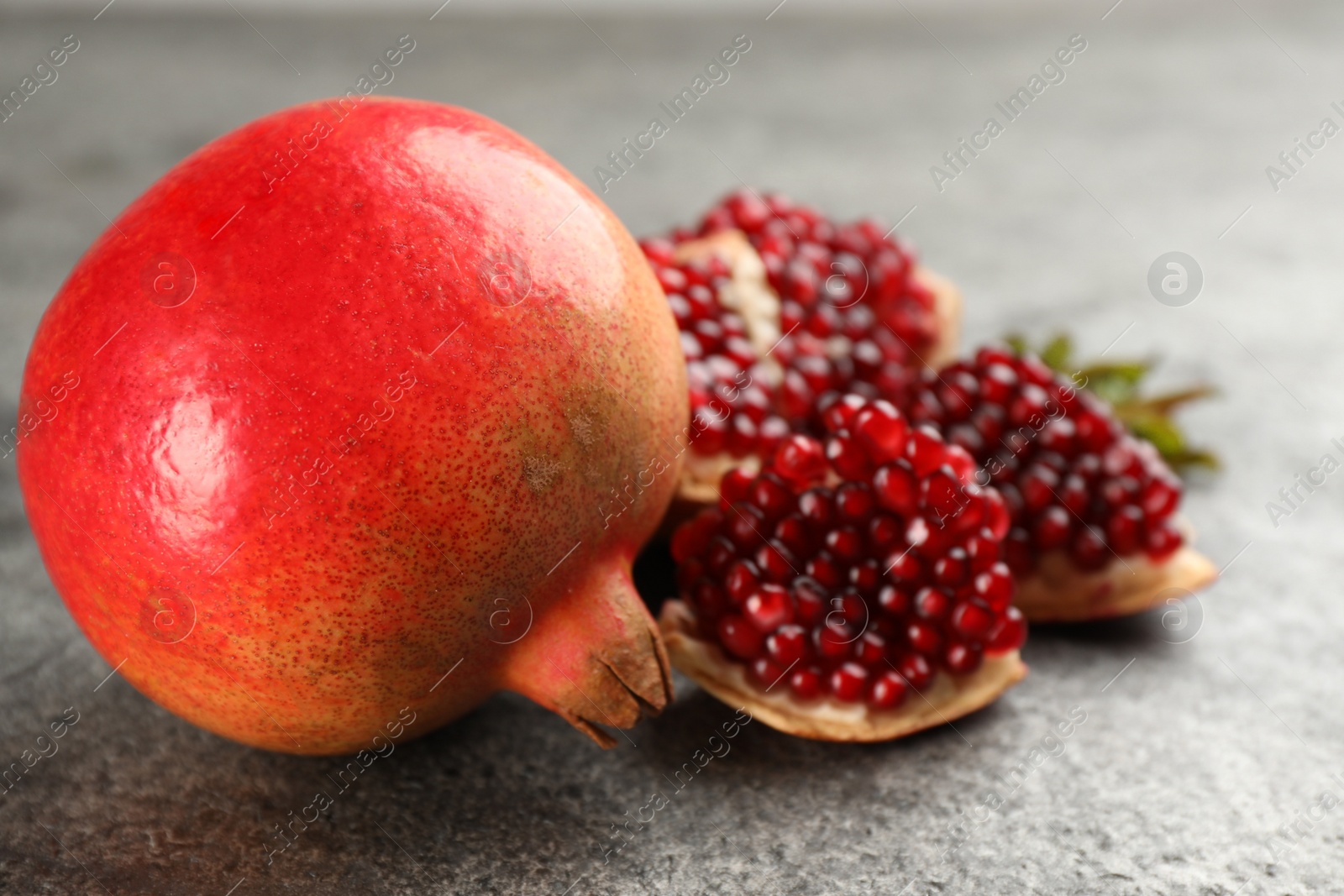 Photo of Delicious ripe pomegranates on grey table, closeup