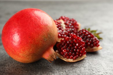 Delicious ripe pomegranates on grey table, closeup