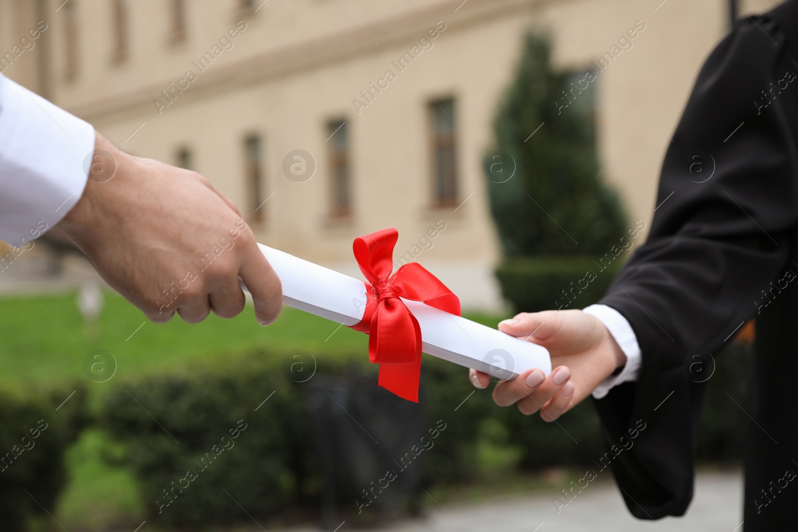 Photo of Student receiving diploma during graduation ceremony outdoors, closeup