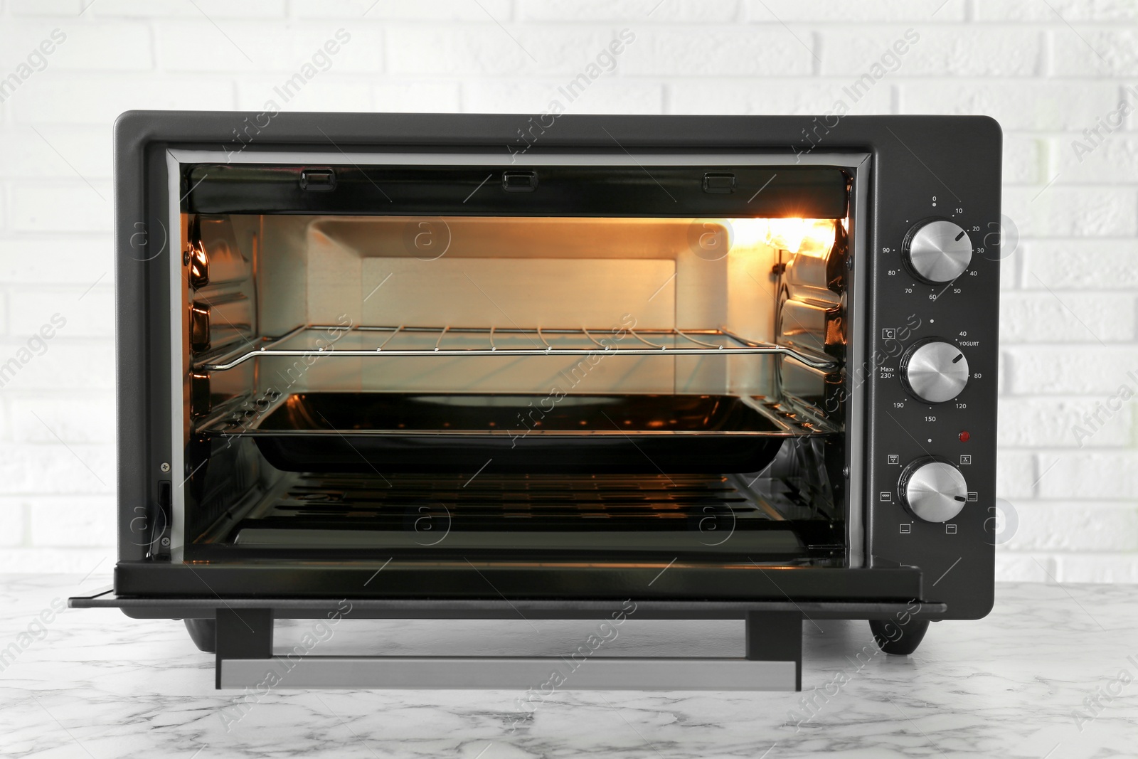 Photo of One electric oven on white marble table near brick wall