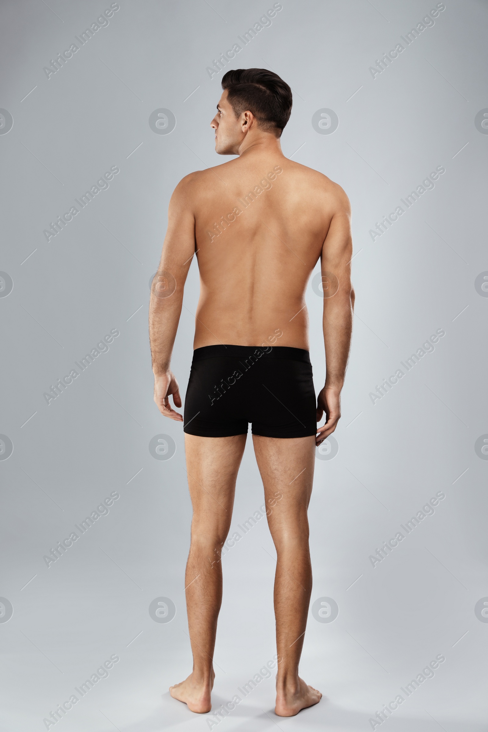 Photo of Handsome man in black underwear on light grey background, back view