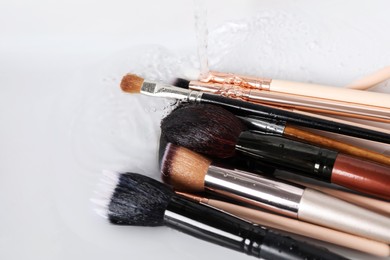 Washing makeup brushes under stream of water in sink, closeup