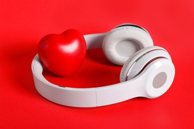 Photo of Modern headphones and heart on red background. Listening love music songs