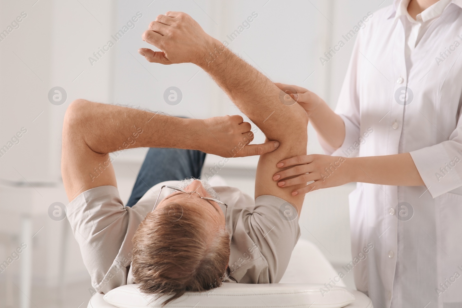 Photo of Professional orthopedist examining patient's arm in clinic