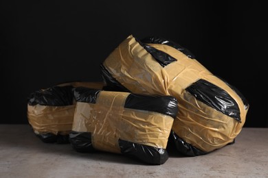 Photo of Smuggling and drug trafficking. Packages with narcotics on grey table against black background