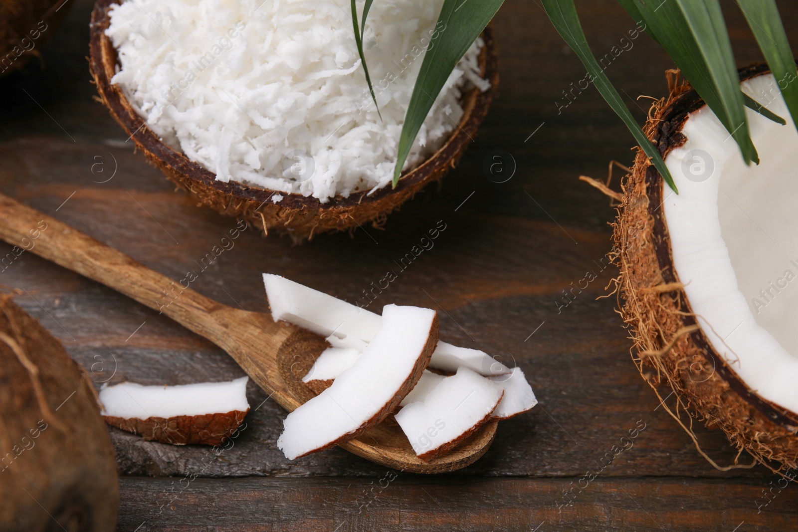 Photo of Coconut flakes, spoon and nut on wooden table