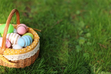 Easter celebration. Painted eggs in wicker basket on green grass, space for text