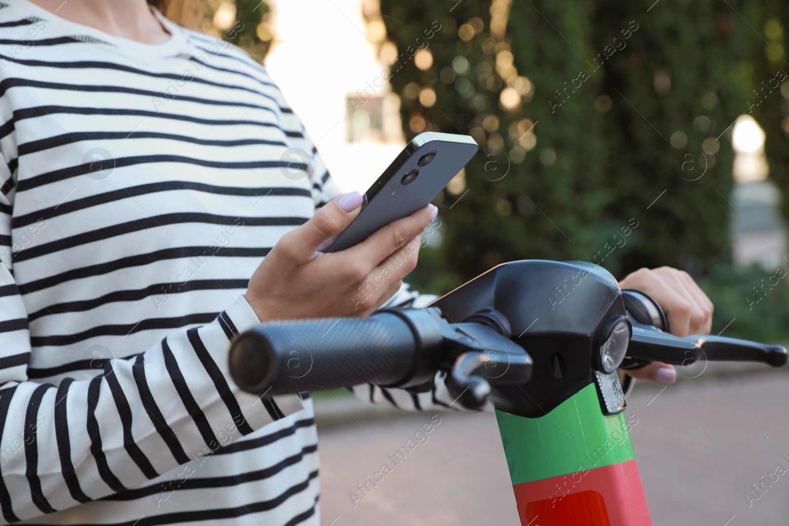 Photo of Woman using smartphone to pay and unblock electric kick scooter outdoors, closeup