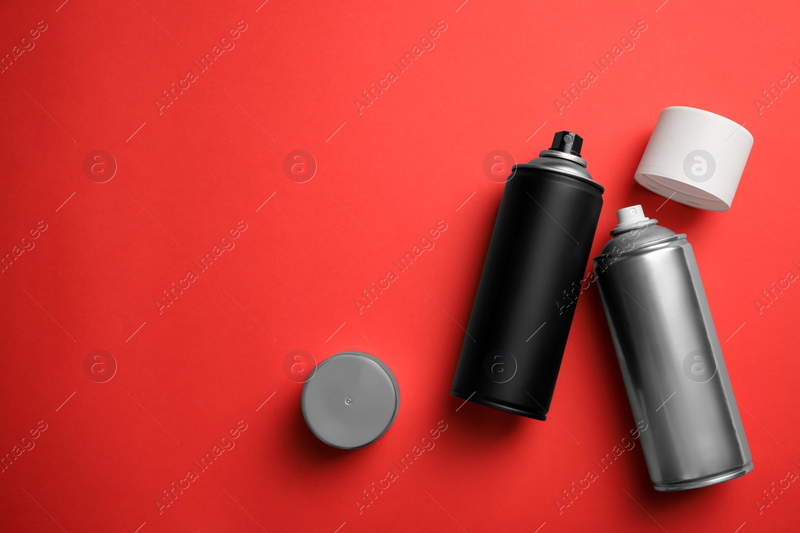 Photo of Cans of different spray paints on red background, flat lay with space for text. Graffiti supplies