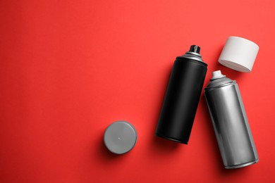 Photo of Cans of different spray paints on red background, flat lay with space for text. Graffiti supplies