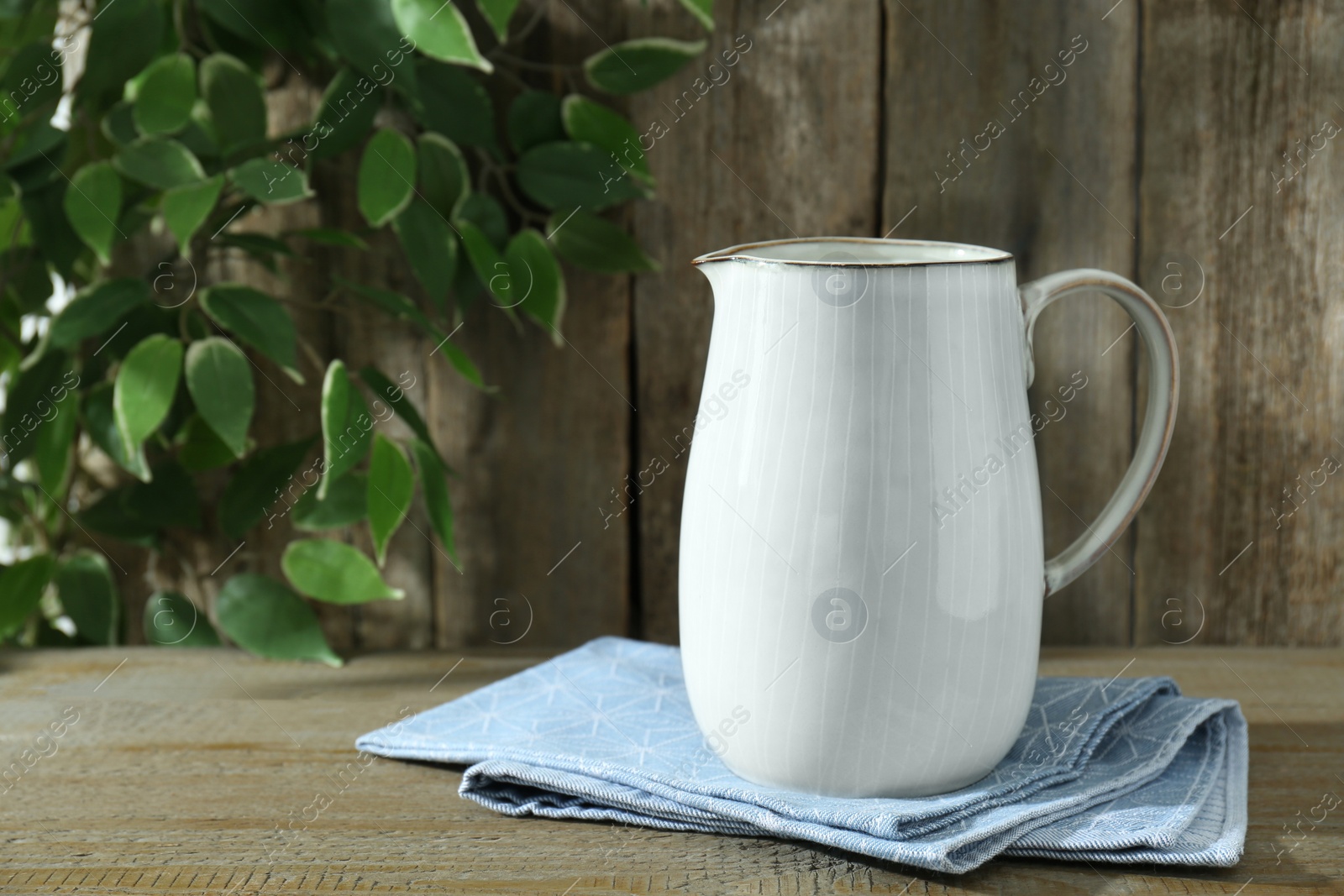 Photo of One white jug on wooden table, space for text