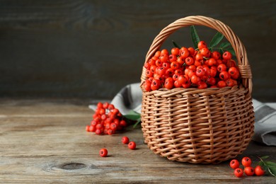 Fresh ripe rowan berries with green leaves on wooden table, space for text