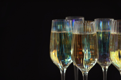 Photo of Glasses of champagne on black background, closeup. Space for text