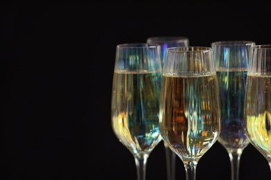 Glasses of champagne on black background, closeup. Space for text