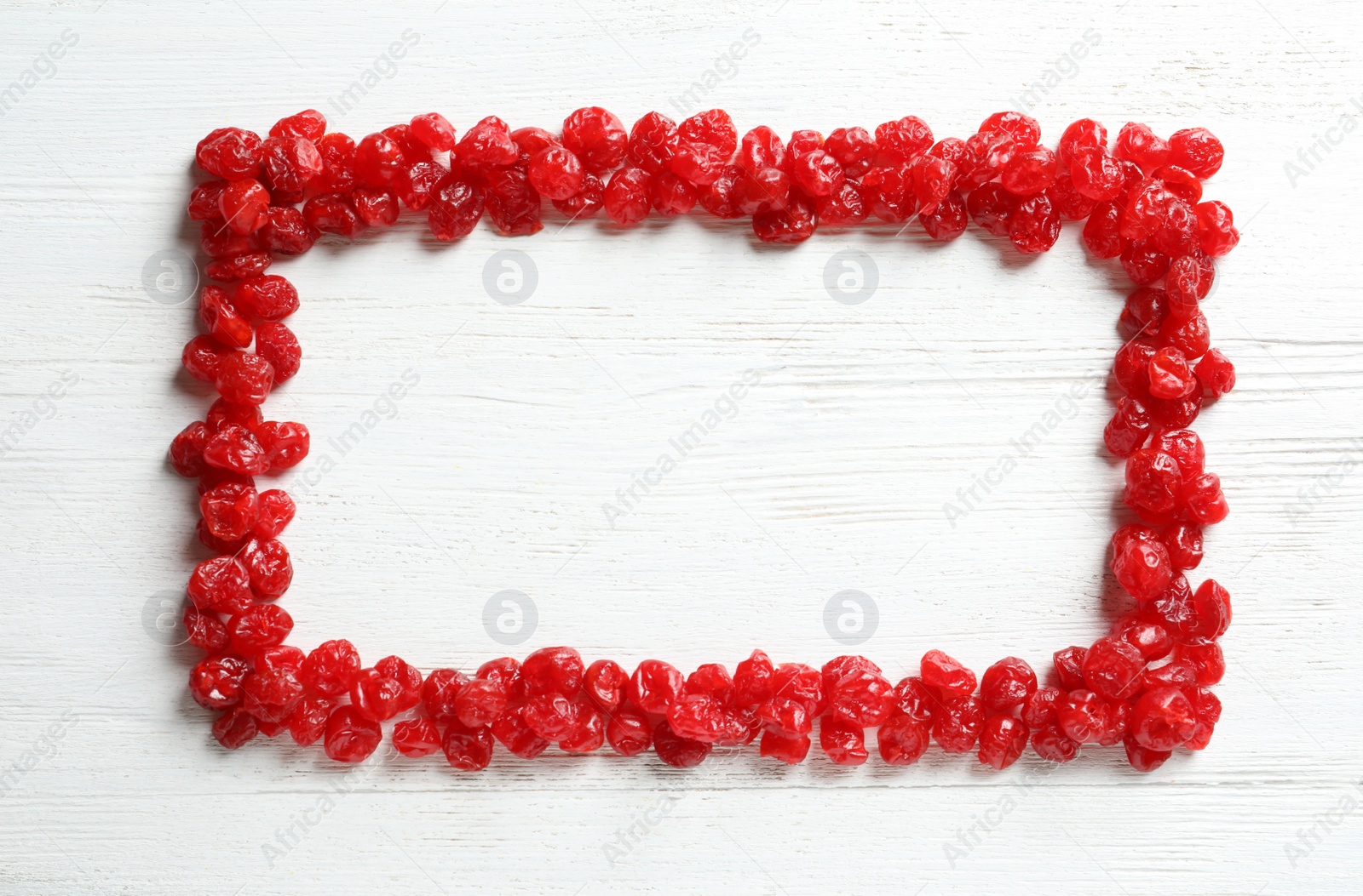 Photo of Frame of cherries on wooden background, top view with space for text. Dried fruit as healthy snack