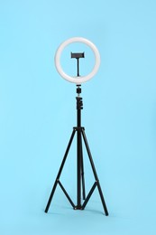 Modern tripod with ring light on blue background