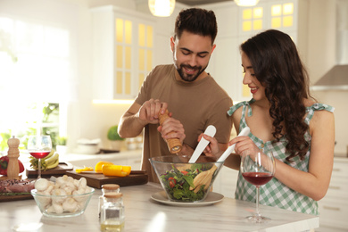Photo of Lovely young couple cooking salad together in kitchen