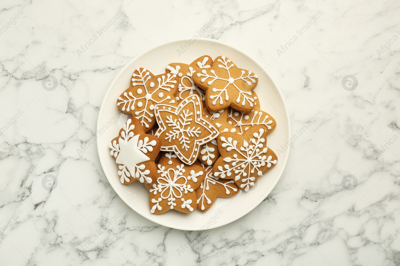 Photo of Tasty star shaped Christmas cookies with icing on white marble table, top view