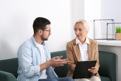 Photo of Woman having conversation with man on sofa in office. Manager conducting job interview with applicant