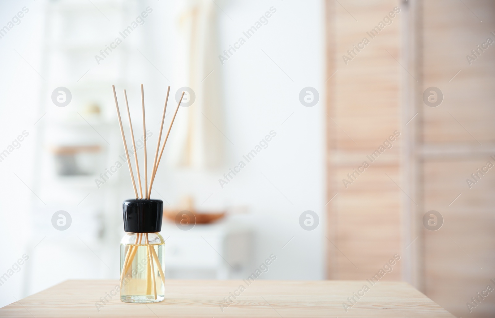 Photo of Aromatic reed air freshener on table against blurred background