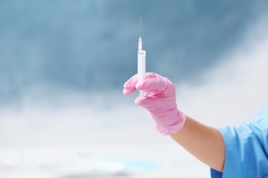 Doctor in medical glove with syringe on color background. Space for text