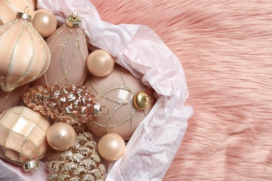 Collection of beautiful Christmas tree baubles on pink faux fur, top view