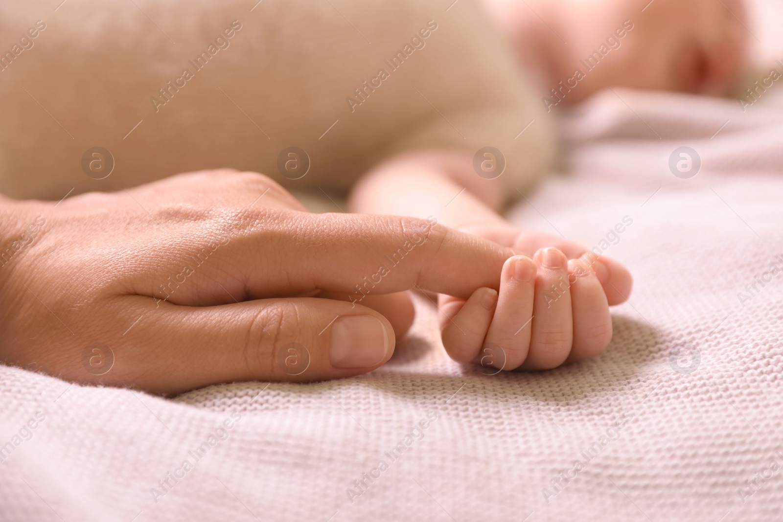 Photo of Mother and her newborn baby on light grey knitted plaid, closeup