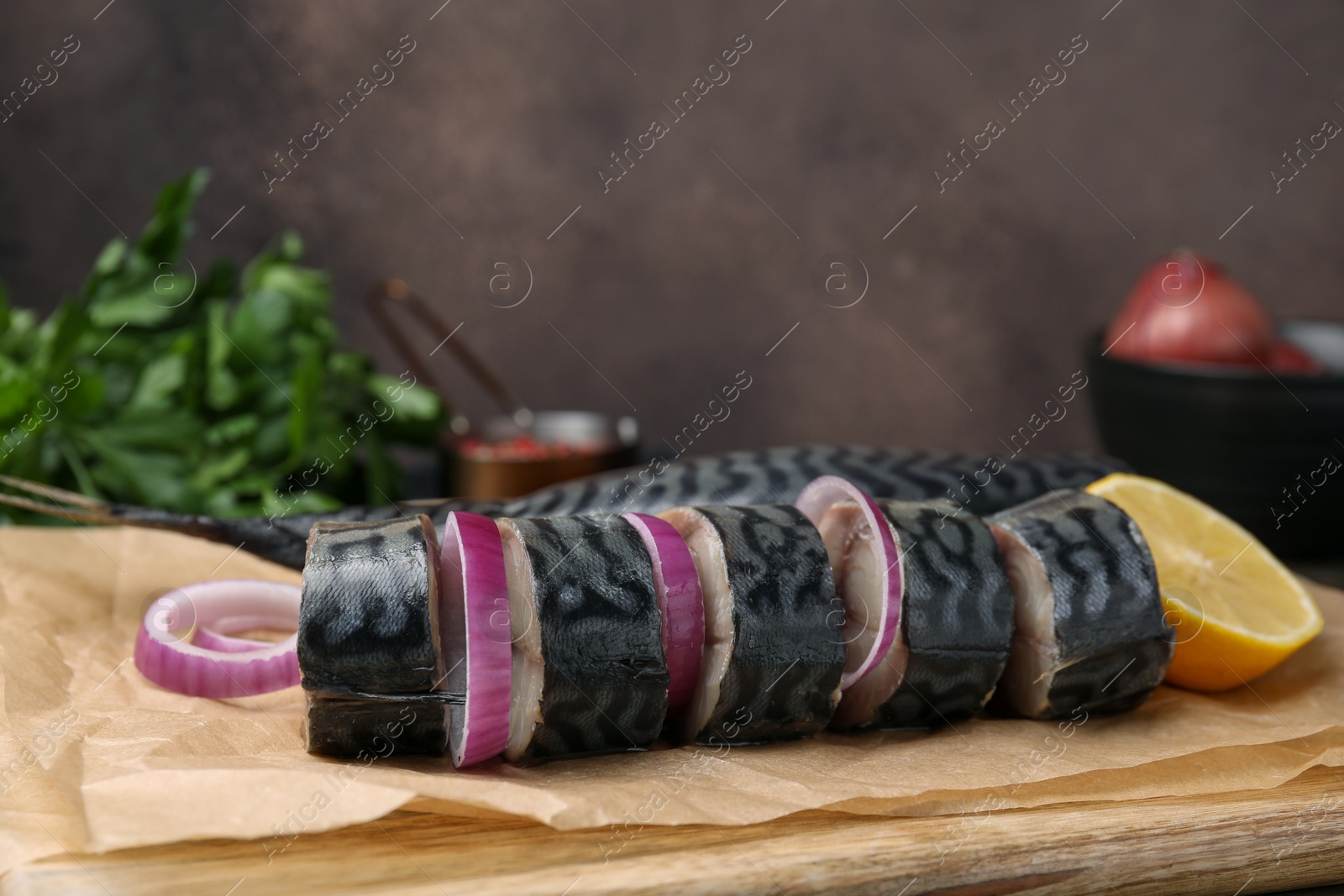 Photo of Tasty salted mackerel, onion and lemon on parchment, closeup